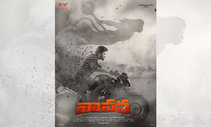 First look poster of the socio-fantasy film Vanara showing hero Avinash Thiruveedhula riding a bike with Hanuman depicted behind him as a divine protector