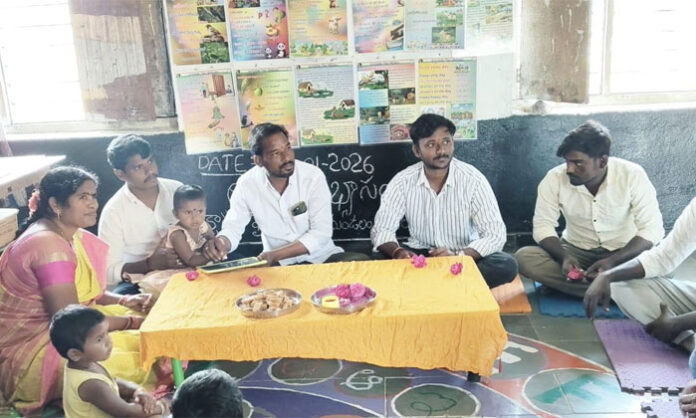 Sarpanch Bestha Durgachalam helping children write letters during Aksharabhyasam at Gangireddulaguda Anganwadi center.