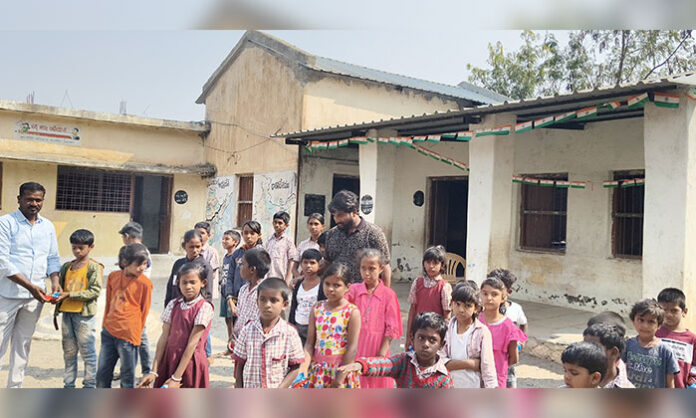 Former councilor Thudum Ganesh distributing biscuits and chocolates to primary school students during former Chief Minister KCR's grand birthday celebrations.