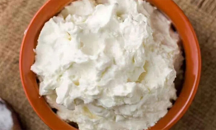 Person struggling to sleep at night while checking phone, highlighting myth about eating butter before bedtime