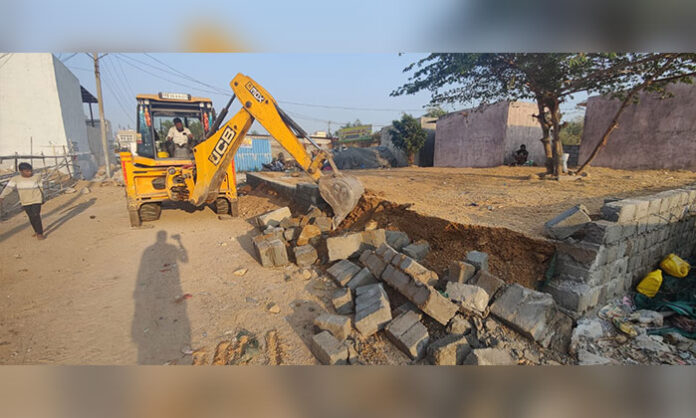 Revenue officials demolish illegal constructions on government land in Jawahar Nagar using JCB machines under GHMC jurisdiction
