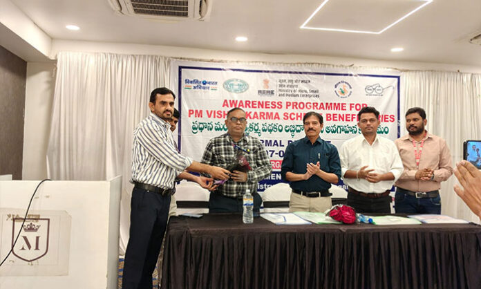 Officials explaining benefits of Pradhan Mantri Vishwakarma Scheme to beneficiaries during awareness program