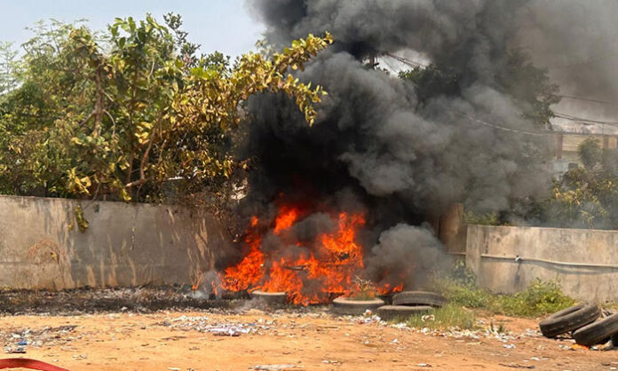 Fire breaking out at a private bus parking lot in Jangaon with thick smoke spreading across nearby residential areas.