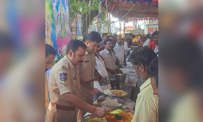 DCP and ACP distributing food to devotees during Hanuman Jayanti annadanam at Vasthu Ganapathi Temple in Jangaon.
