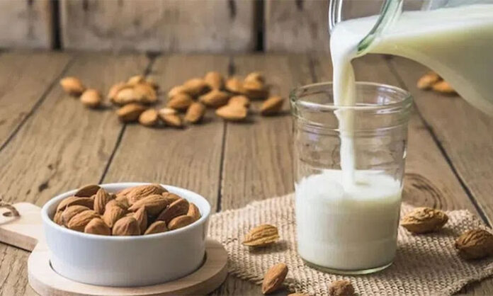 Glass of chilled homemade almond milk garnished with almonds and cashews, a healthy cooling drink ideal for summer hydration.