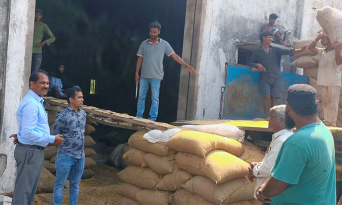 Additional Collector V Ramulu inspecting rice mill and instructing officials on speeding up grain unloading process in Mancherial district