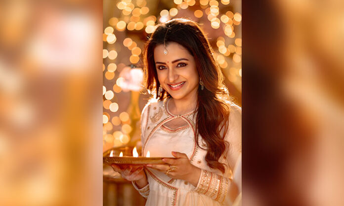 Trisha Krishnan in Vishwambhara birthday poster holding lamps with warm festive background from Chiranjeevi UV Creations film