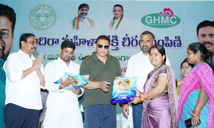 Minister Mohammad Azharuddin distributes sarees to women beneficiaries at the Indira Mahila Shakti program held at Banjara Bhavan in Hyderabad.