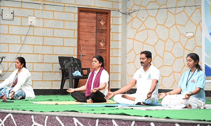 Participants perform yoga asanas during the International Yoga Day celebrations held at Ambedkar Bhavan in Nirmal town.