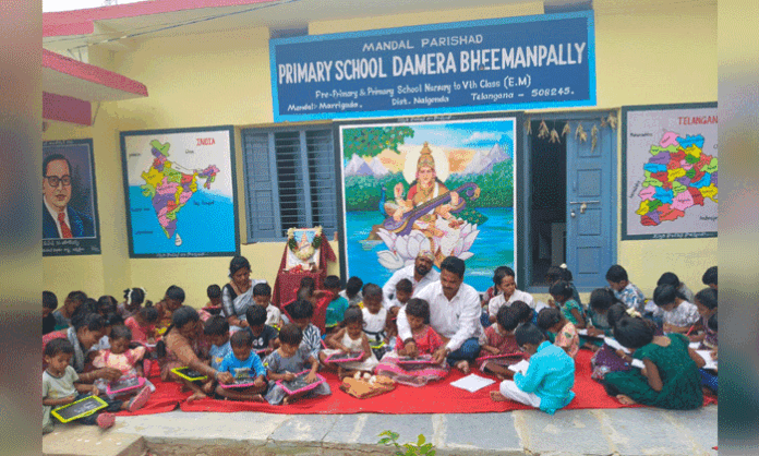 Young children participate in a mass Aksharabhyasam ceremony at Damera Bheemanapally Primary School while receiving free slates and slate pencils from the Indira Foundation.