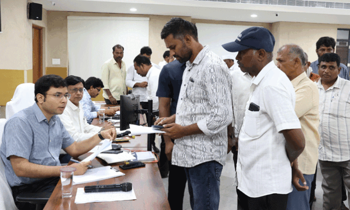 District Collector Bhavesh Mishra receives public grievance applications during the Prajavani program and directs officials to resolve pending complaints promptly.