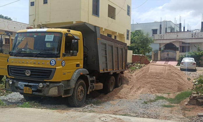 Tipper trucks allegedly transporting sand through the Dundubhi stream area during nighttime amid complaints of illegal sand movement and dust pollution.