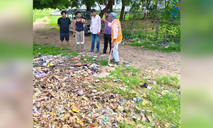 Municipal sanitation workers clear garbage near a temple in Sofinagar Colony, Nirmal, after a residents' complaint.