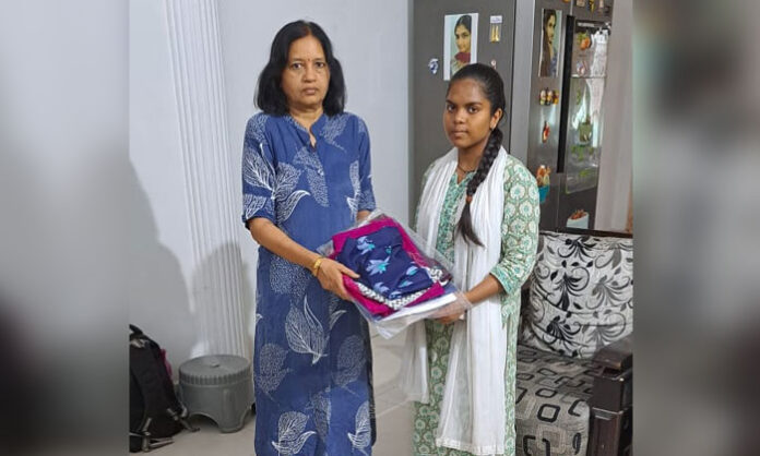 Sri Akanksha Charitable Trust President Palaparthi Sandhya Rani distributes new clothes and notebooks to an underprivileged student.