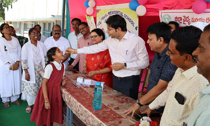 Nirmal District Collector Bhavesh Mishra distributes Albendazole tablets to students during the National Deworming Day program.