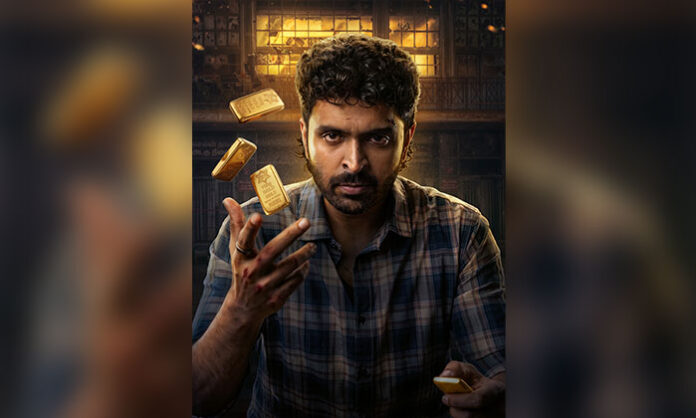 Vikram Prabhu sits with an intense expression while tossing gold bars in the first-look poster of City of Gold, directed by Siddharth.